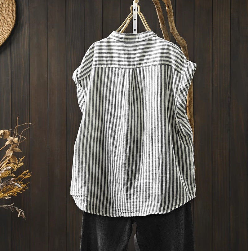 Striped sleeveless shirt hanging on a wooden hook against a wooden wall.