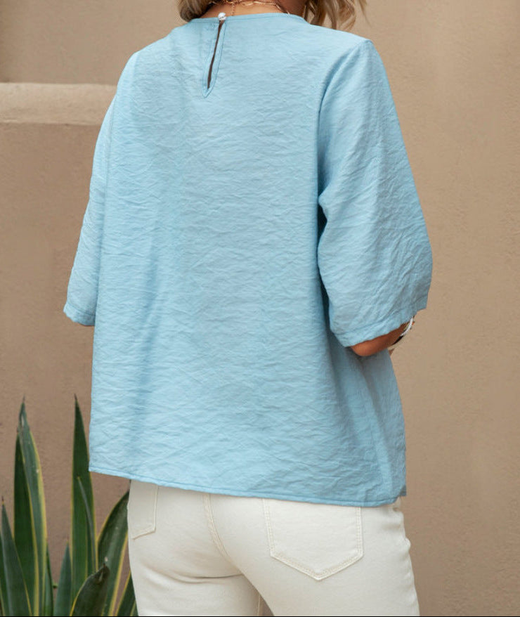 Person wearing a light blue shirt and white pants against a beige background